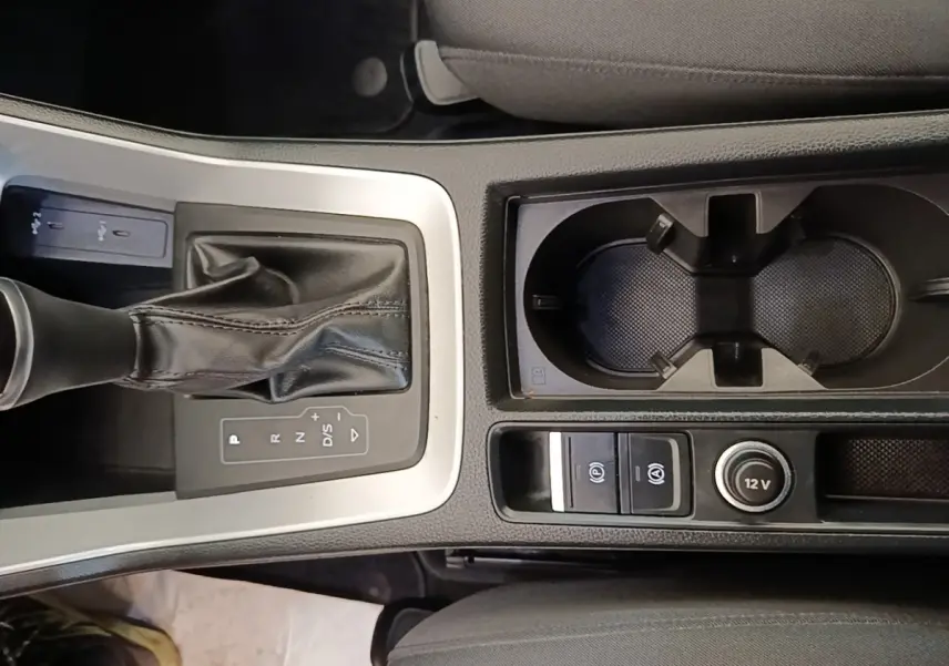 Vue plongeante sur la console centrale noire de l'Audi Q3 45 TFSI E avec levier de vitesses et porte-gobelets.