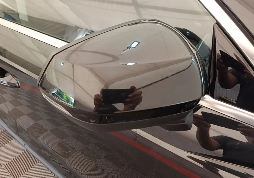 Rétroviseur côté gauche noir brillant d’un Audi Q3 hybride rechargeable 2023, reflet de l’environnement intérieur visible.