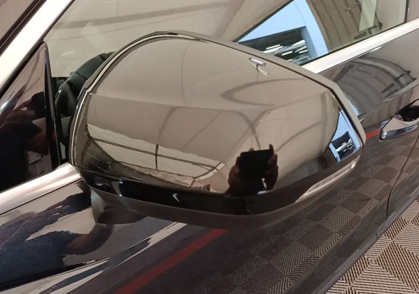 Rétroviseur droit noir brillant d’un Audi Q3 hybride rechargeable 2023, avec carrosserie sombre et poignée visible.