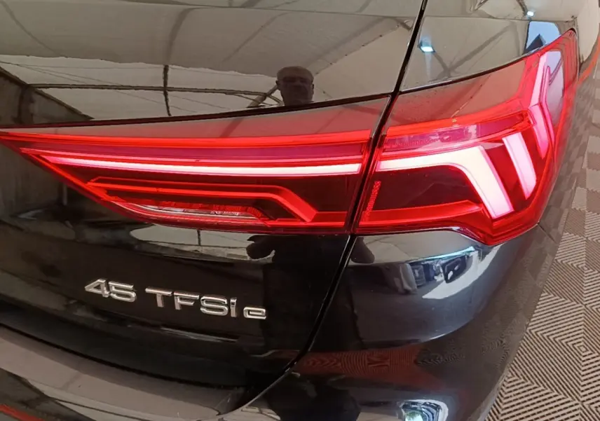 Gros plan sur le feu arrière droit rouge d’un Audi Q3 hybride rechargeable noir avec badge 45 TFSI e.