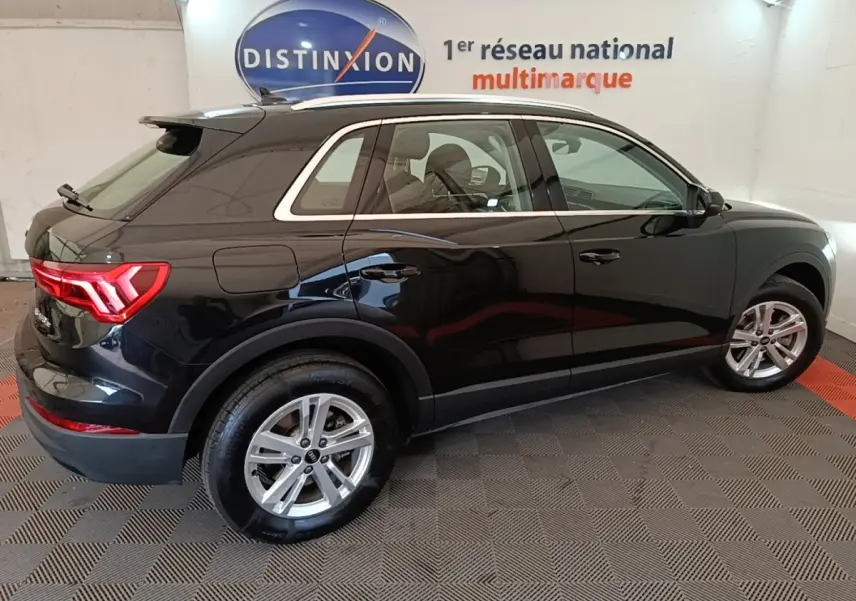 Audi Q3 hybride rechargeable noir vue de profil côté droit en intérieur avec jantes alliage et feux arrière LED allumés.