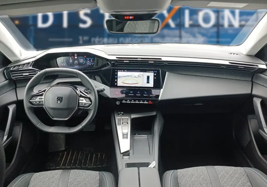 Intérieur Peugeot 408 Hybrid 2024 vu de face, tableau de bord moderne avec écran tactile et volant cuir multifonction.