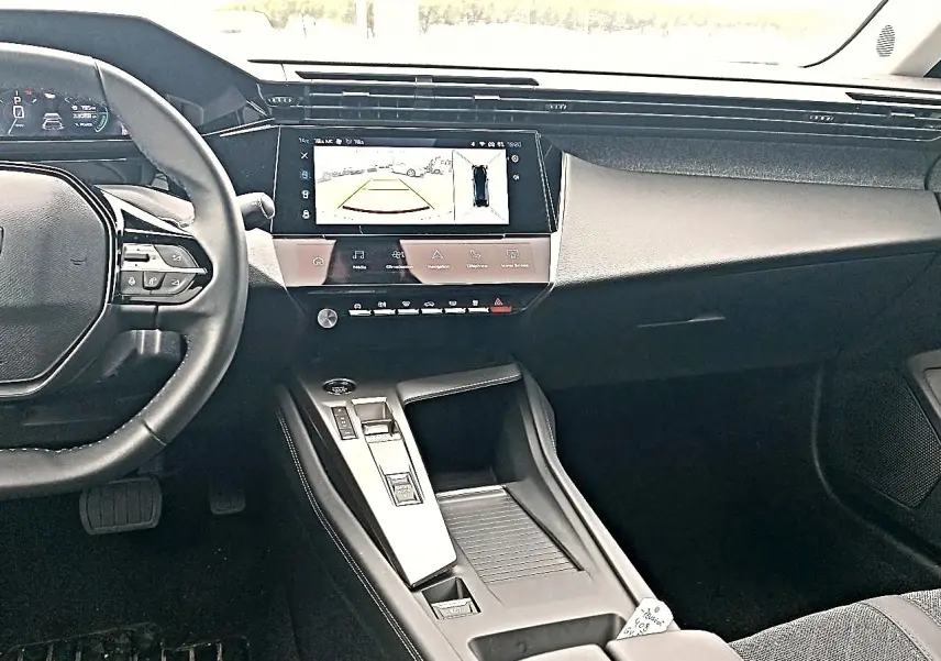 Vue intérieure avant du tableau de bord et console centrale de la Peugeot 408 Hybrid 145 allure, avec écran tactile et volant cuir multifonction.