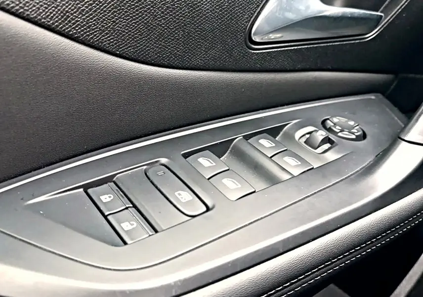 Gros plan sur la commande des vitres et rétroviseurs côté gauche en noir à l'intérieur d'une Peugeot 408 Hybrid 145 allure 2024.