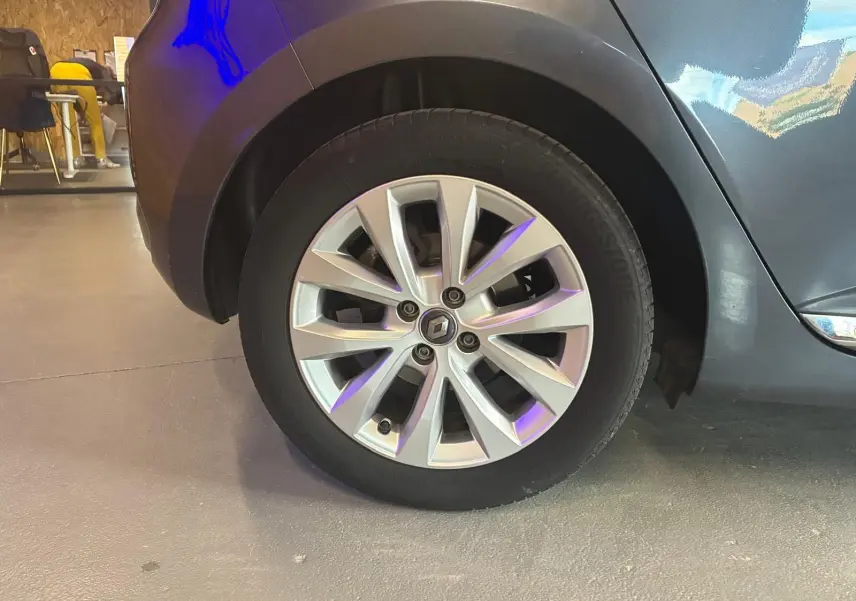 Gros plan sur la roue avant gauche d'une Renault Clio gris 2020 avec jante alliage et logo Renault visible.