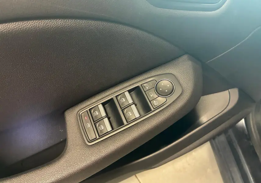 Gros plan sur la commande des vitres côté conducteur d'une Renault Clio gris 2020 avec intérieur tissu gris-noir.