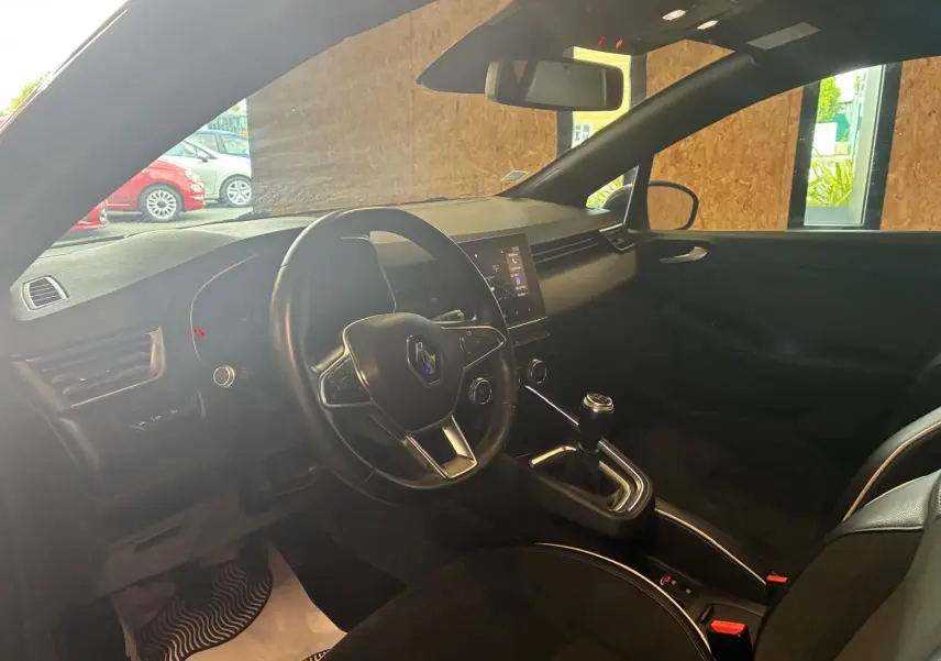 Vue intérieure côté conducteur de la Renault Clio gris 2020, volant multifonction et levier de vitesse manuel visibles.