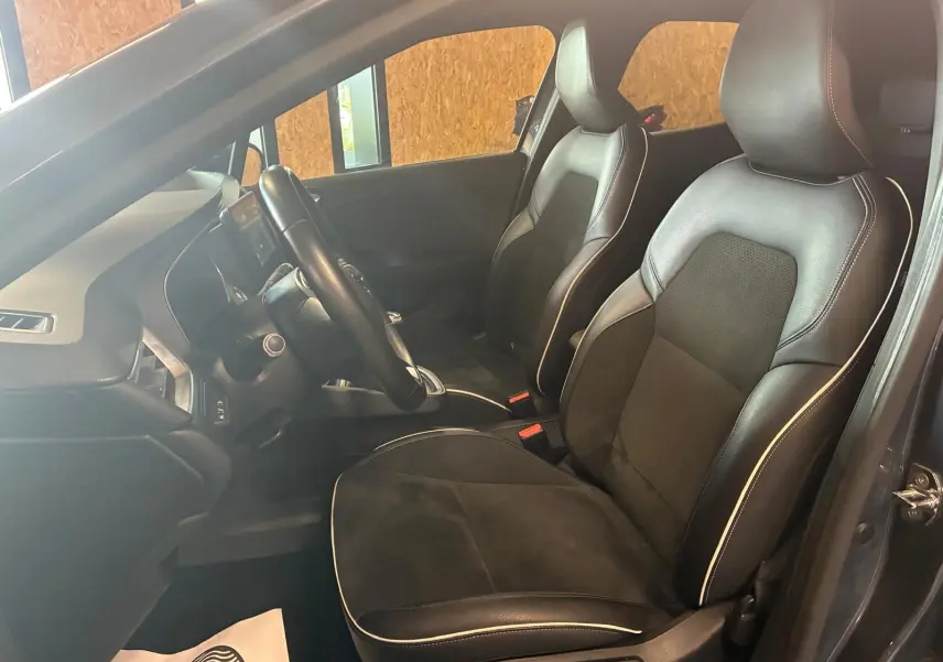 Vue intérieure côté conducteur de la Renault Clio gris 2020, sièges tissu noir avec surpiqûres blanches et volant multifonction.