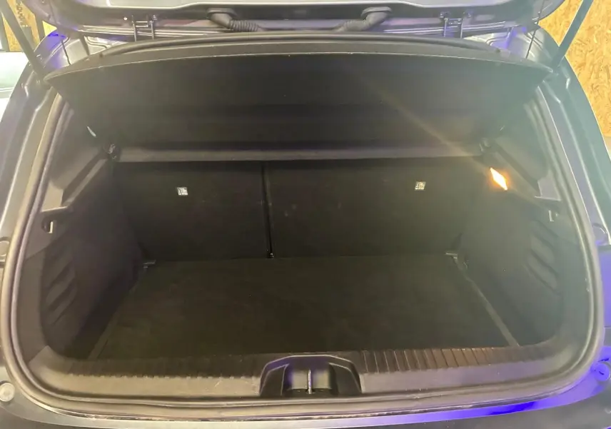 Coffre ouvert d'une Renault Clio gris 2020, vue arrière montrant un espace de chargement vide et éclairé.