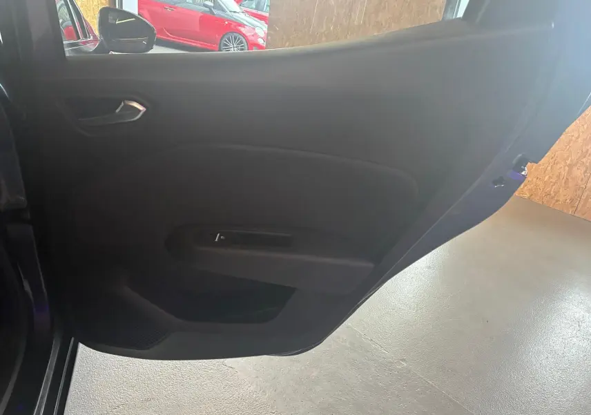 Vue intérieure de la porte arrière gauche d'une Renault Clio gris 2020 avec poignée et panneau noir simple.