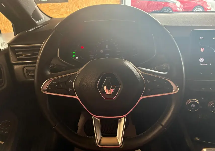 Volant noir de Renault Clio 2020 avec commandes intégrées, tableau de bord numérique et écran tactile visible à droite.