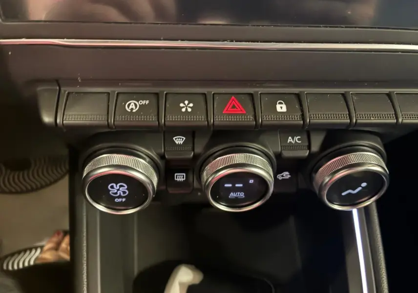 Détail des commandes de climatisation et boutons de sécurité sur la console centrale d'une Renault Clio gris 2020.