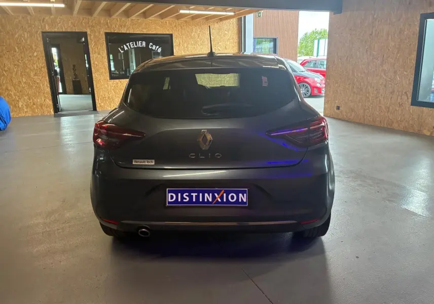 Vue arrière d'une Renault Clio gris foncé 2020, avec logo Renault et plaque Distinxion visible en intérieur d'atelier.