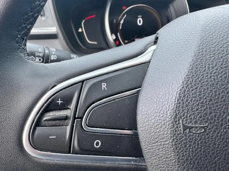 Gros plan sur les commandes au volant cuir noir du Renault Kadjar 2020, avec tableau de bord en arrière-plan flou.