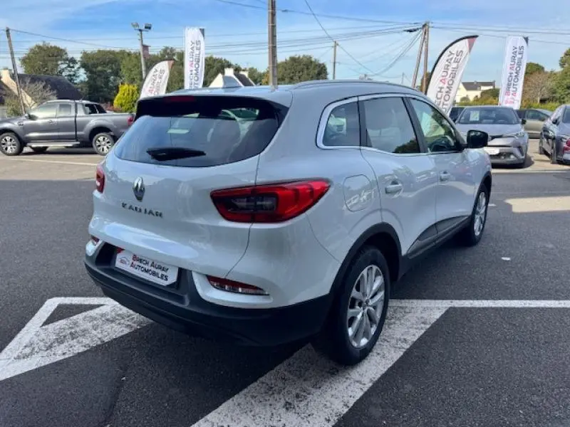Renault Kadjar blanc vu en 3/4 arrière droit sur parking avec feux arrière LED et jantes alu visibles.