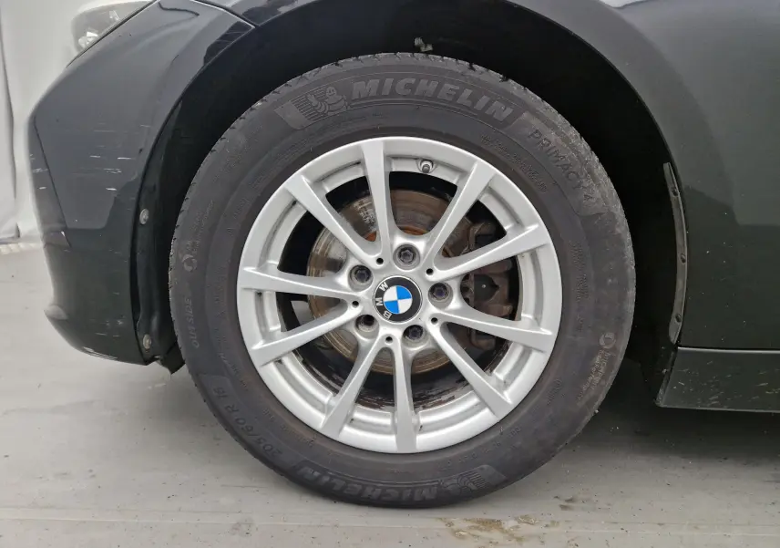 Gros plan sur la roue avant gauche noire d'une BMW Série 3 316D 2014 avec jante alliage argent et pneu Michelin.