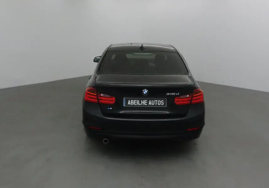Vue arrière d'une BMW Série 3 316d noire de 2014 avec feux rouges et plaque Abeilhe Autos.