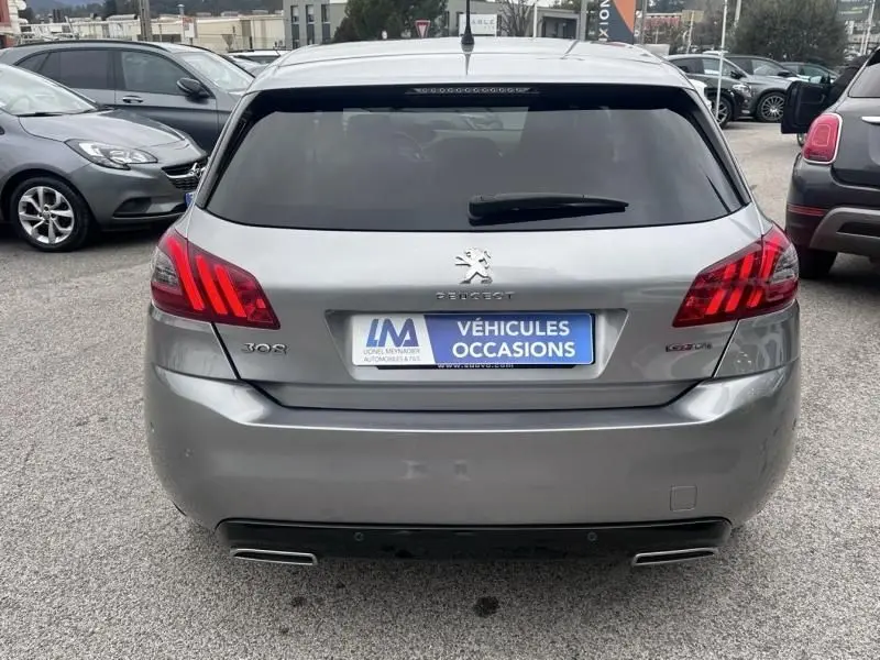 Vue arrière d'une Peugeot 308 gris métal de 2019 avec feux arrière à griffes rouges et double sortie d'échappement.
