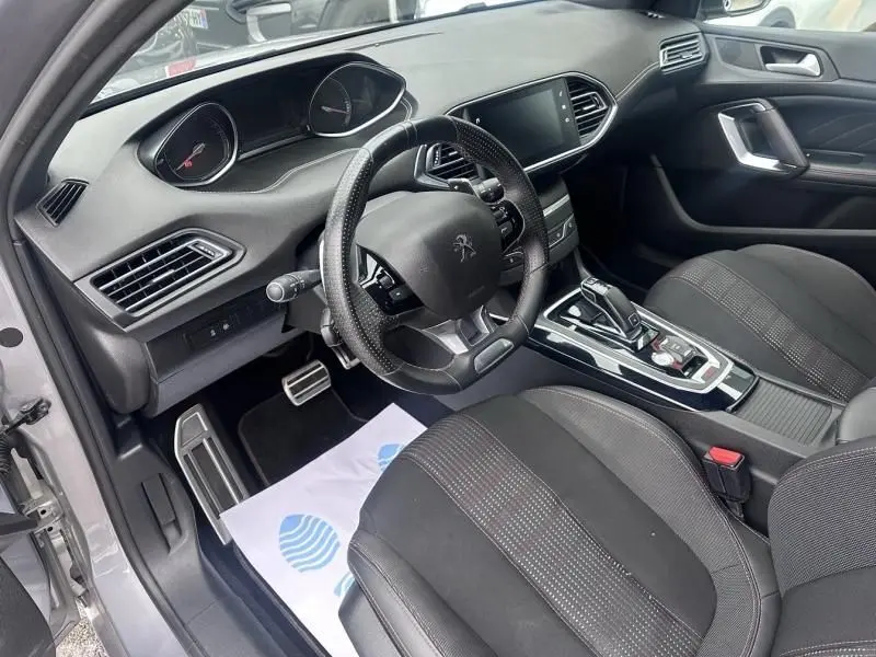 Vue intérieure côté conducteur de la Peugeot 308 gris métal 2019, avec volant compact, écran tactile et console centrale automatique.