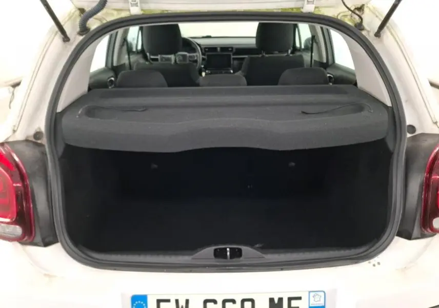 Vue arrière du coffre ouvert d'une Citroën C3 blanche, montrant l'intérieur vide et la tablette cache-bagages noire.