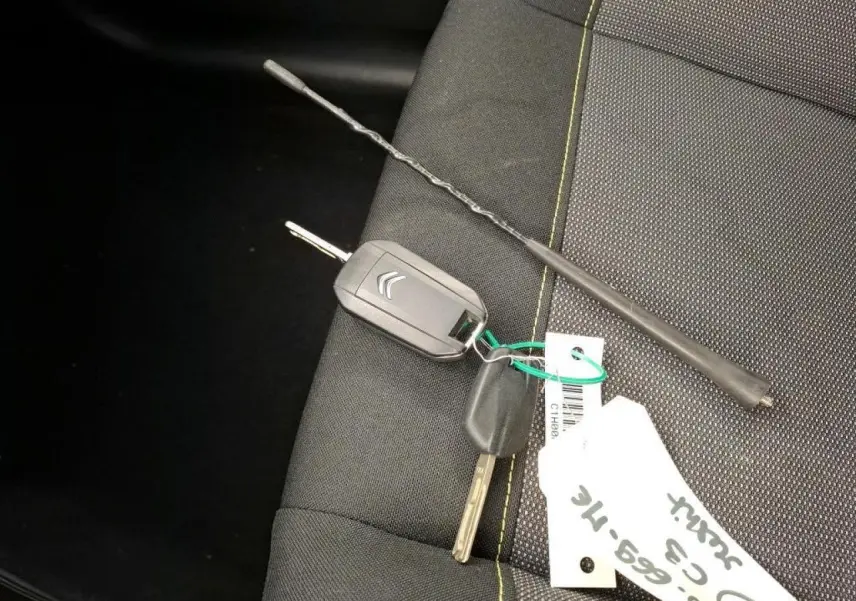 Clé et télécommande Citroën posées sur siège tissu gris foncé avec surpiqûres jaunes, intérieur Citroën C3 2021.