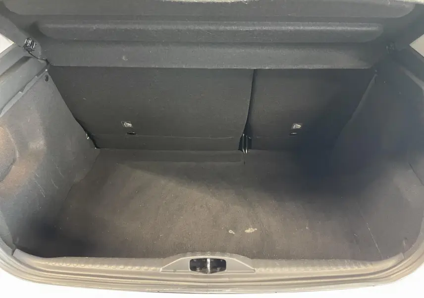 Vue intérieure du coffre noir vide de la Citroën C3 blanche, montrant la banquette arrière rabattue partiellement.