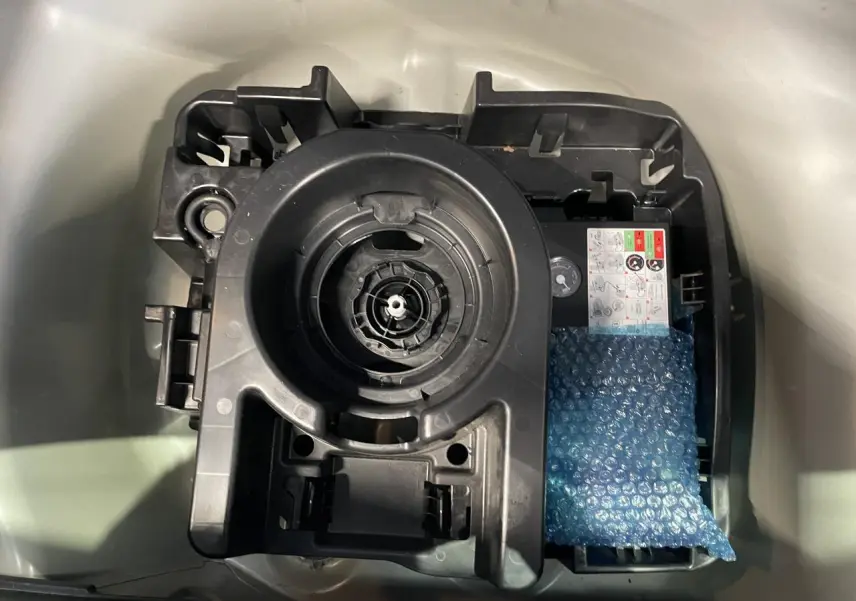 Gros plan sur le compartiment de rangement sous le coffre d'une Citroën C3 blanche, montrant le support de roue de secours.