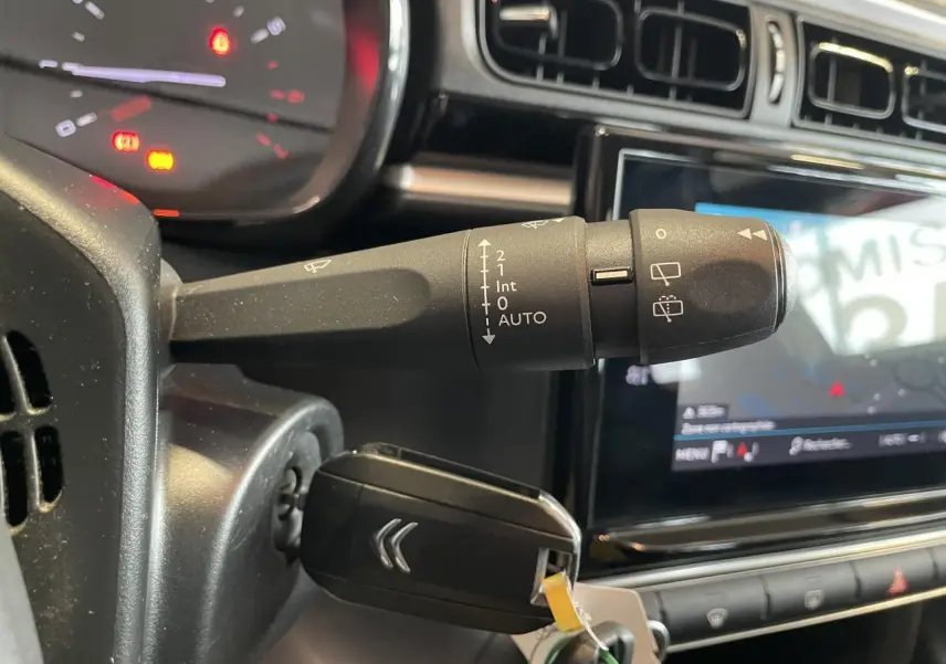 Gros plan sur la commande d’essuie-glace et clé insérée dans le contacteur d’une Citroën C3 2021, intérieur noir.