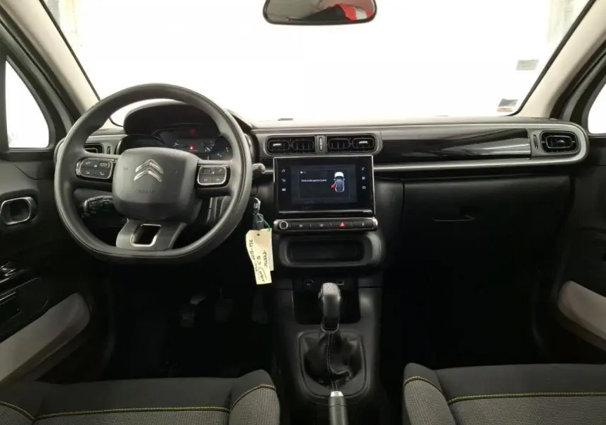 Vue intérieure avant de la Citroën C3 blanche, tableau de bord noir brillant avec écran tactile et volant multifonction.