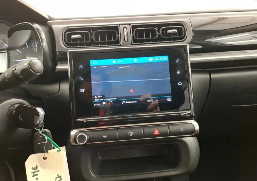 Vue rapprochée de la console centrale noire brillante avec écran tactile et aérateurs rectangulaires d'une Citroën C3 blanche.