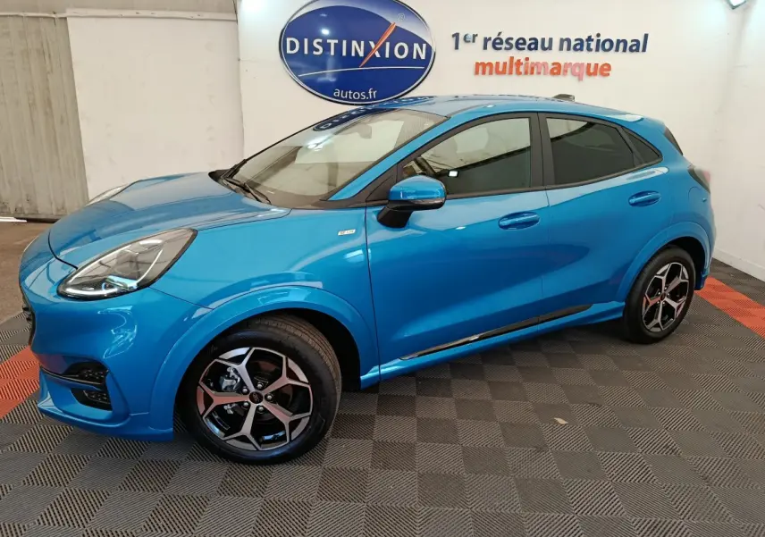 Vue latérale droite d'un Ford Puma bleu 2025 ST-LINE avec jantes alliage et vitres teintées en intérieur showroom.