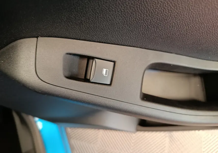 Gros plan sur l'interrupteur de lève-vitre côté conducteur d'une Ford Puma bleu 2025, intérieur noir.