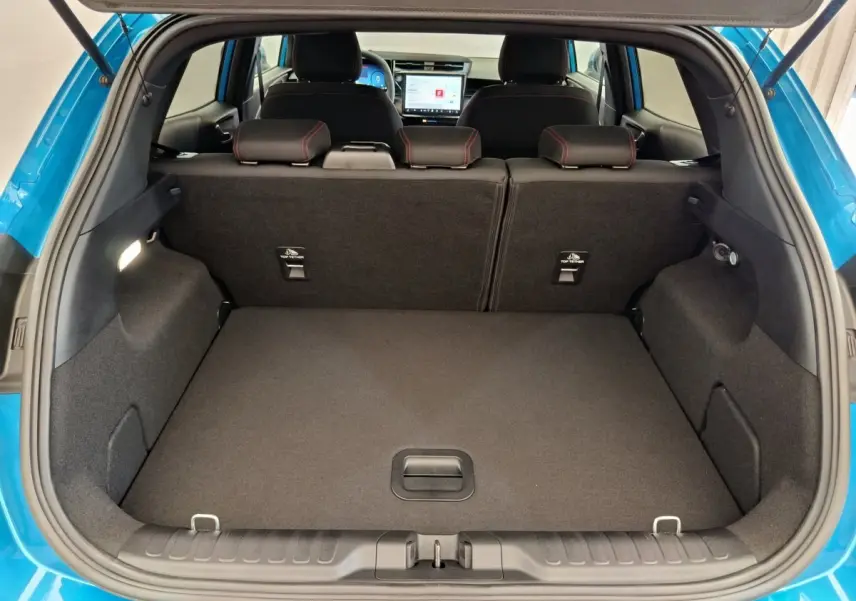 Vue arrière du coffre ouvert d’un Ford Puma bleu 2025, montrant la banquette arrière et l’écran tactile du tableau de bord.