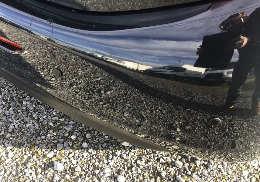 Gros plan sur le pare-chocs arrière noir brillant du Peugeot 208 2018 avec capteurs de recul visibles.