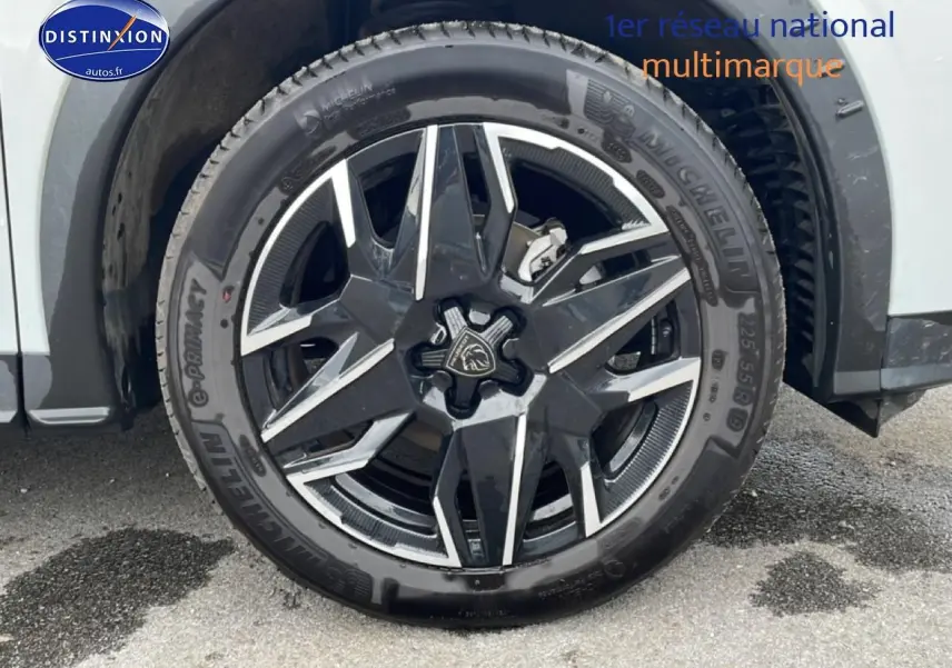 Gros plan sur la roue avant droite avec jante alu noire et argentée du Peugeot 3008 blanc 2025.