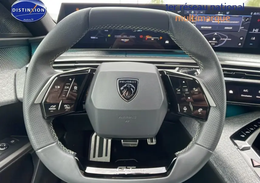 Vue rapprochée du volant cuir multifonction gris avec logo Peugeot et inscription GT sur un Peugeot 3008 blanc 2025.