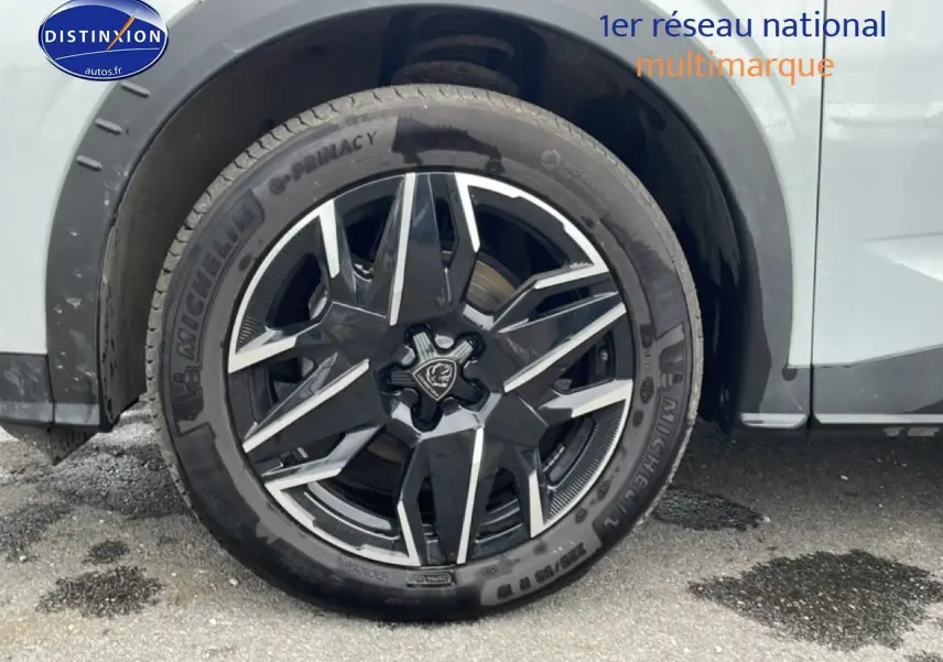 Gros plan sur la roue avant droite du Peugeot 3008 blanc, mettant en valeur la jante alu noire et argentée au design moderne.
