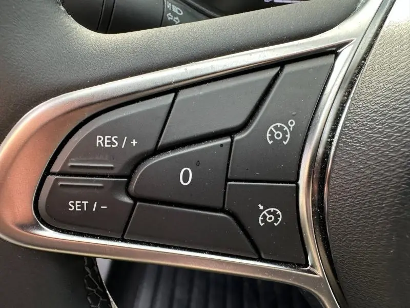 Gros plan sur les commandes noires du régulateur de vitesse au volant de la Renault Clio 1.0 TCe 90ch Evolution 2025.