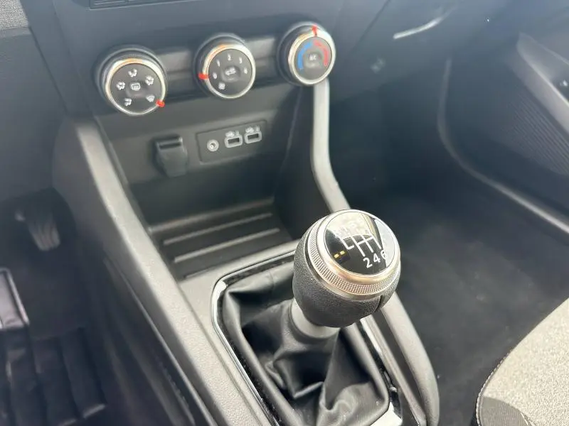 Gros plan sur la commande de boîte manuelle et les commandes de climatisation noires dans le Renault Clio 2025.