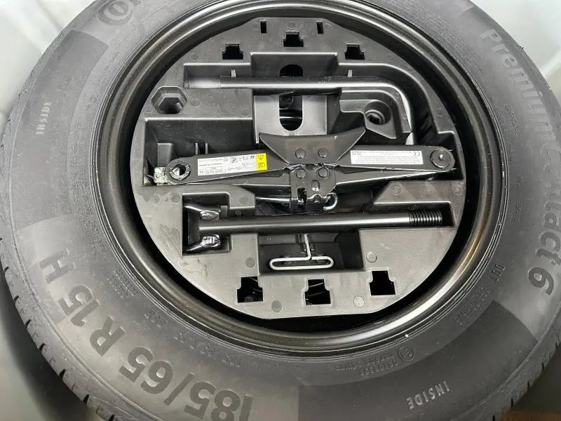 Gros plan sur la roue de secours et le cric noir rangé au centre du pneu Continental 185/65 R15.