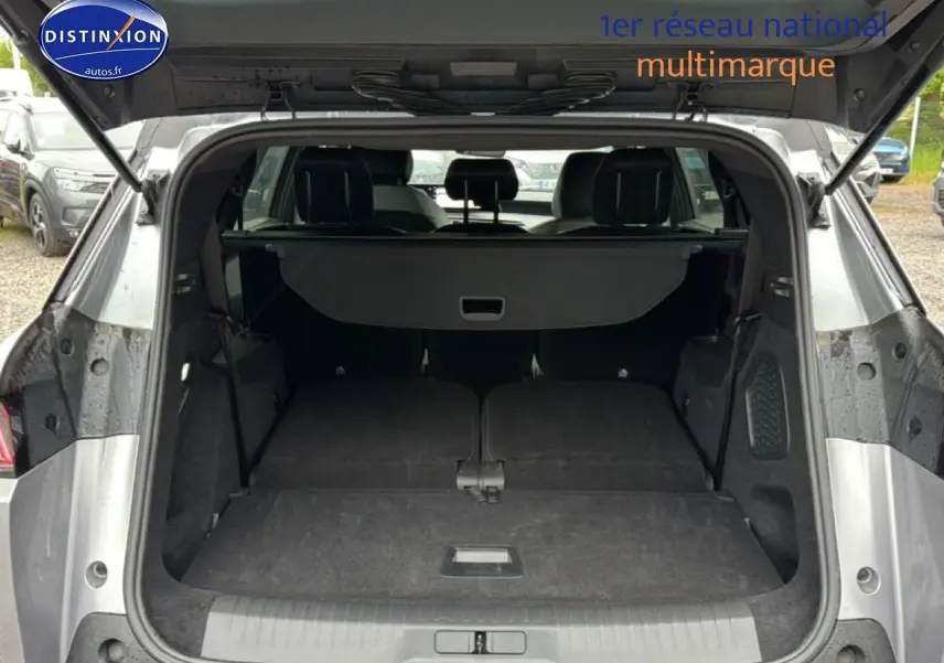 Coffre ouvert vu de l’arrière d’un Peugeot 5008 gris artense avec banquette arrière rabattue à plat.