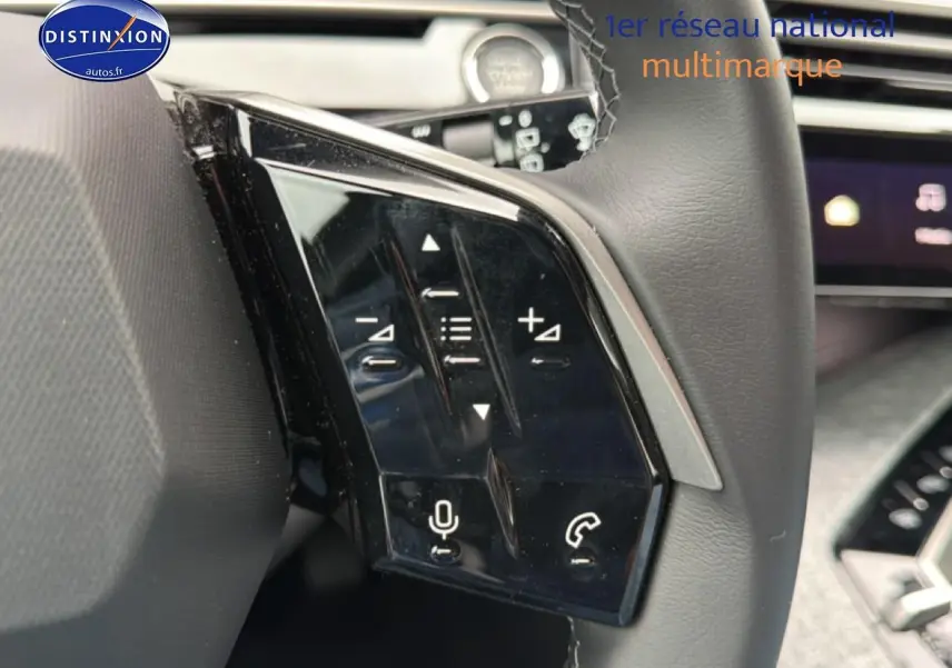 Gros plan sur les commandes vocales et audio au volant cuir du Peugeot 5008 gris Artense, intérieur moderne.