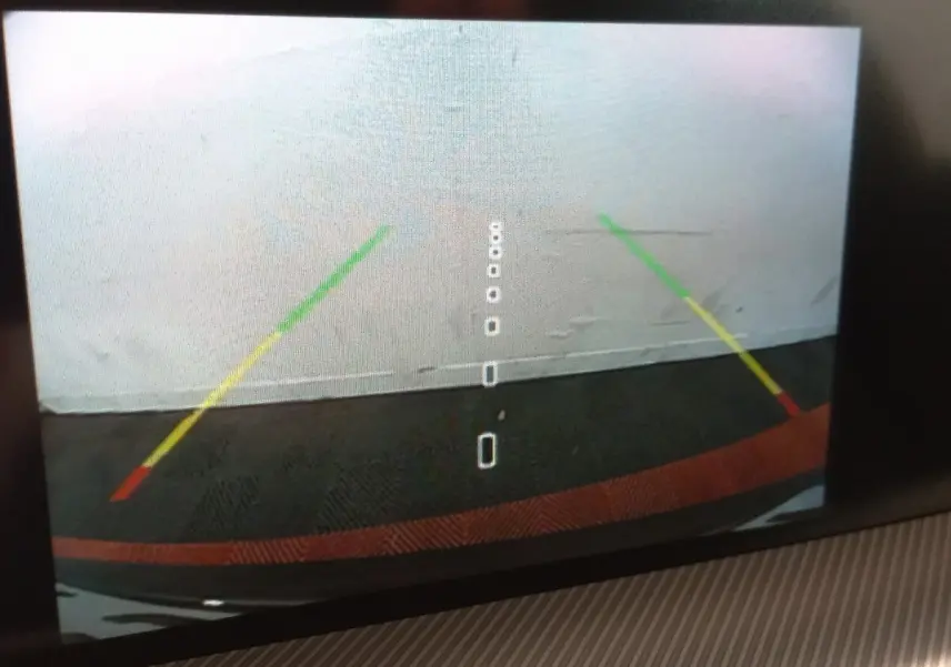 Vue caméra de recul arrière avec guidage coloré sur fond gris, sans visibilité directe du véhicule.