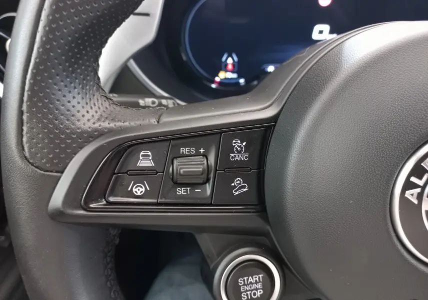 Gros plan sur les commandes multifonctions à gauche du volant cuir perforé de l'Alfa Romeo Stelvio 2024 avec bouton start/stop.