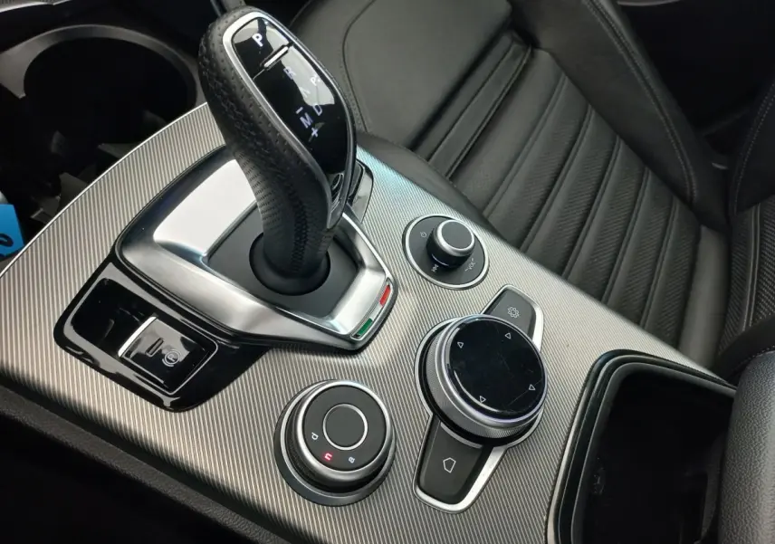 Gros plan sur la console centrale grise et le levier de vitesses automatique de l'Alfa Romeo Stelvio Sprint 2024, intérieur cuir noir.