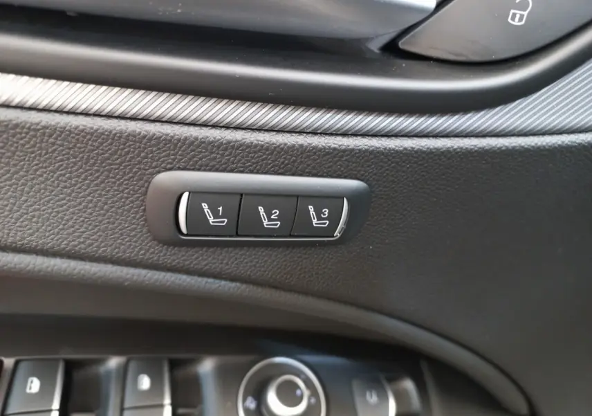 Détail des commandes de mémorisation des sièges sur la porte intérieure noire d'une Alfa Romeo Stelvio gris foncé.