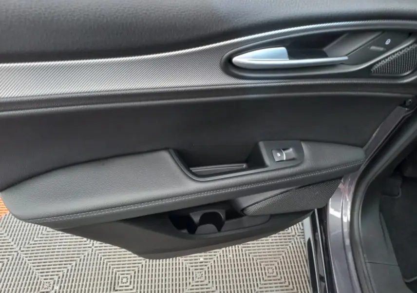 Vue rapprochée de la porte côté droit gris foncé de l'Alfa Romeo Stelvio 2024 avec poignée alu et commande de vitre.