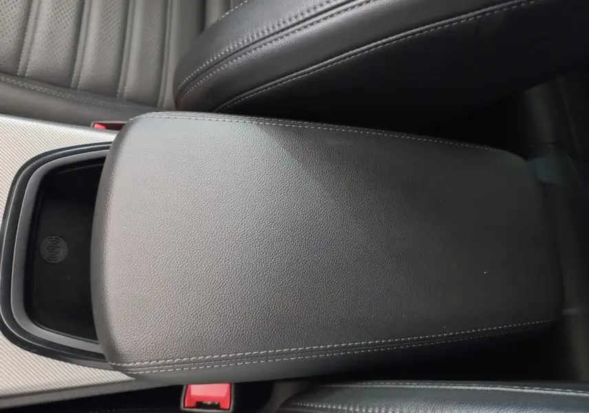 Gros plan sur l'accoudoir central en cuir noir de l'Alfa Romeo Stelvio 2024 avec zone de recharge sans fil visible.