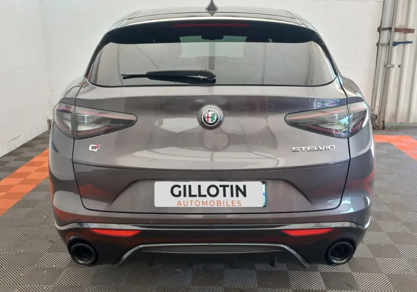 Vue arrière d'un Alfa Romeo Stelvio gris foncé avec double sortie d'échappement et feux arrière LED distinctifs.