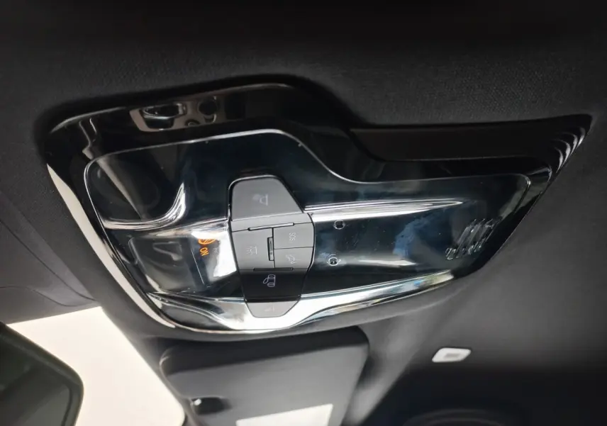 Vue intérieure en plongée du plafonnier noir brillant avec commandes d’éclairage et bouton SOS de l'Alfa Romeo Stelvio gris foncé.
